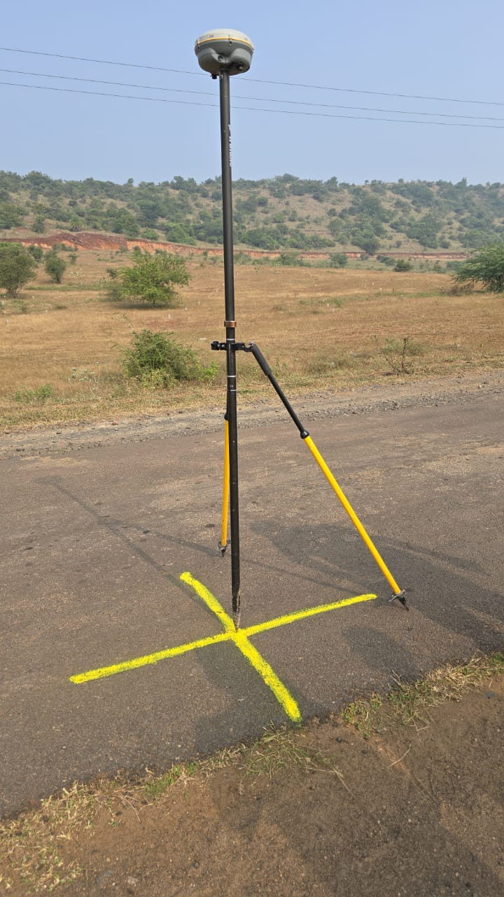 GNSS receiver set over a control point marked with yellow paint on a road
