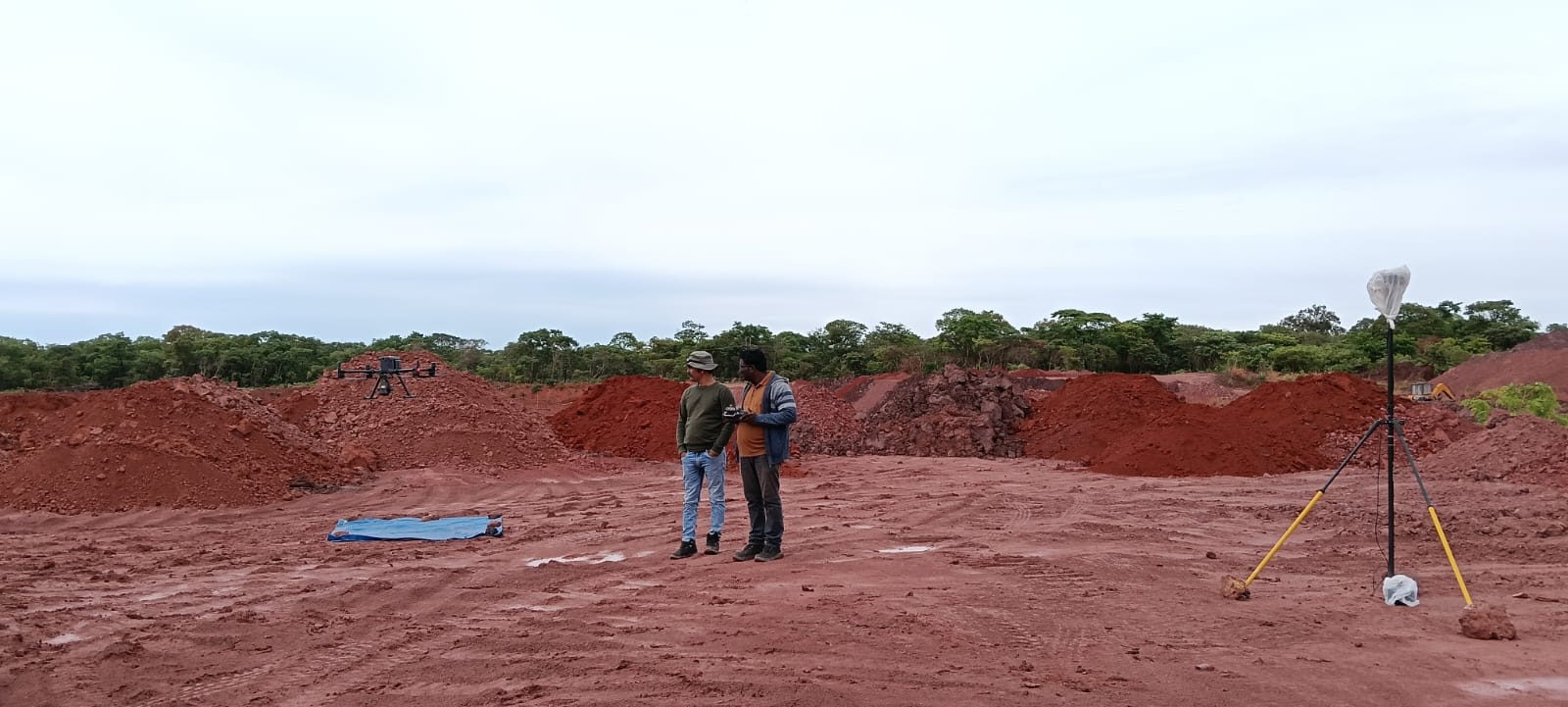 Surveyors planning a LiDAR mission beside laterite spoil heaps at a mine site